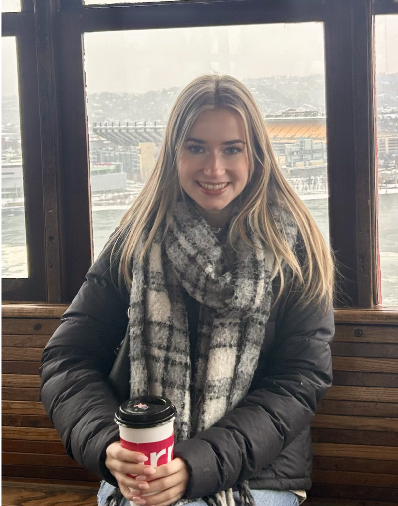 Carling McQuinn smiling and holding a cup of coffee